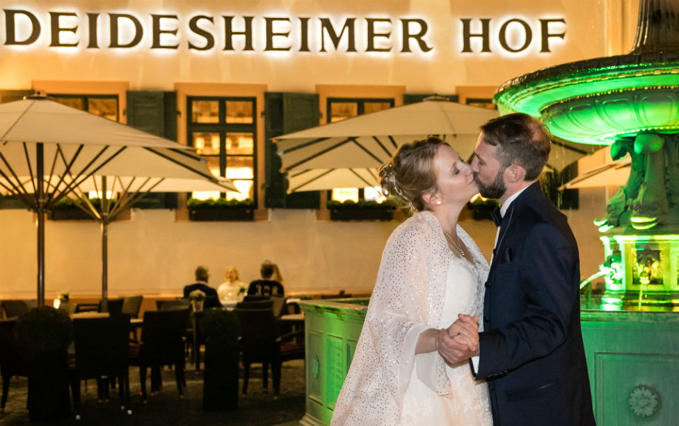 Brautpaarkuss am Abend vor dem beleuchteten Brunnen am Deidesheimer Hof Brautpaarkuss am Abend vor dem beleuchteten Brunnen am Deidesheimer Hof